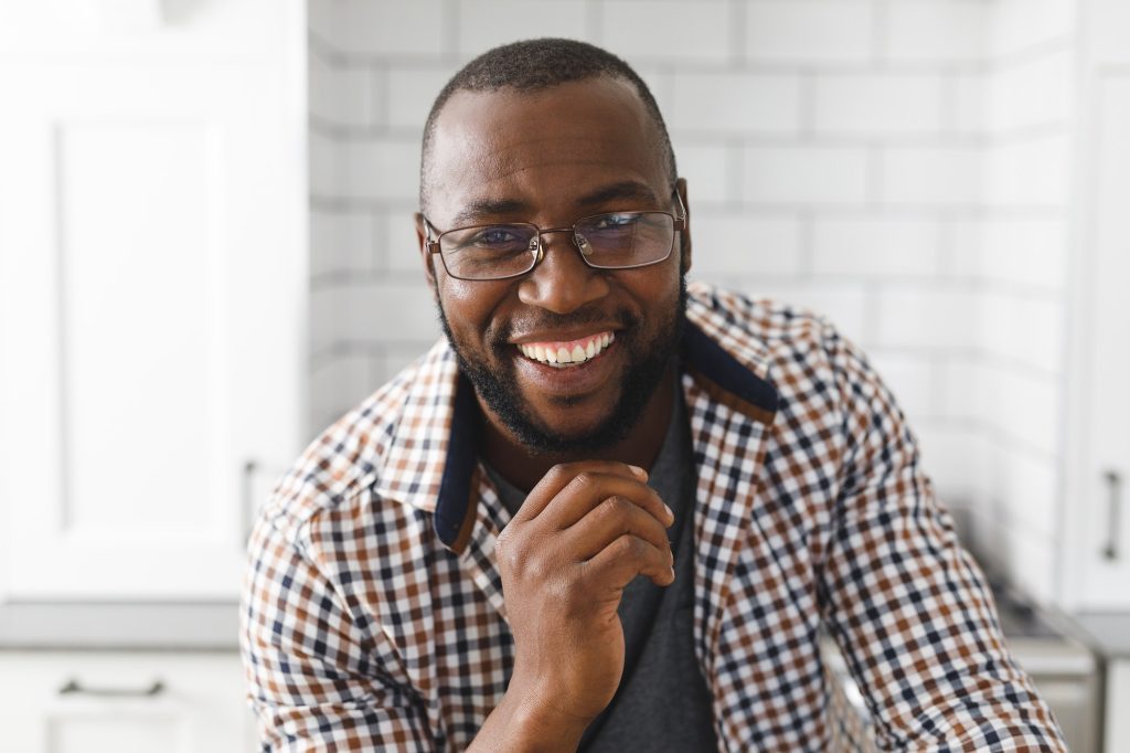 Portrait of happy african american man in kitchen, looking to camera and smiling