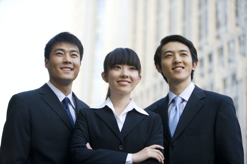 Three business professionals in front of skyscraper
